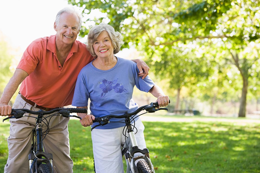 Älteres Paar mit Fahrrädern lächelt in die Kamera